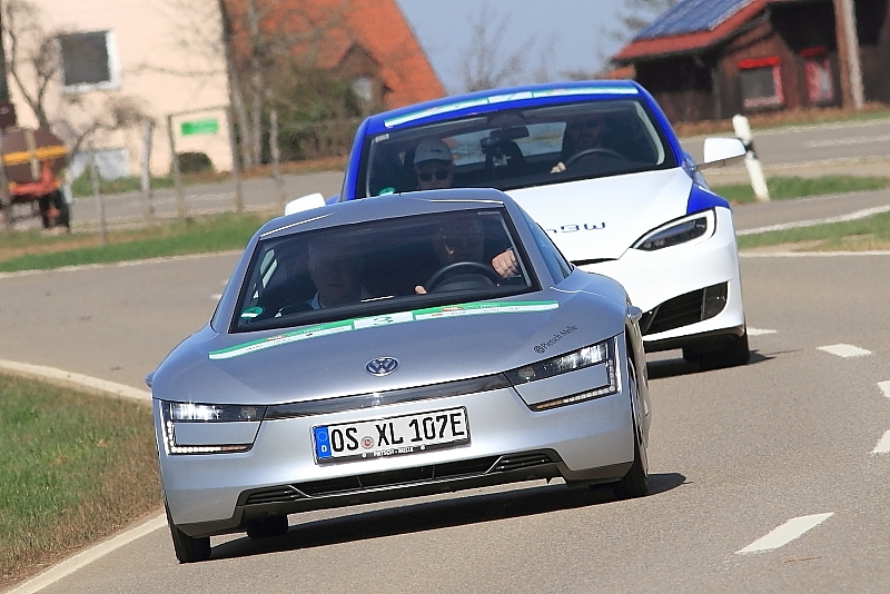 6   Rainer Teders und Marcus Heine rollen im VW XL 1 (2014) vor einem Tesla